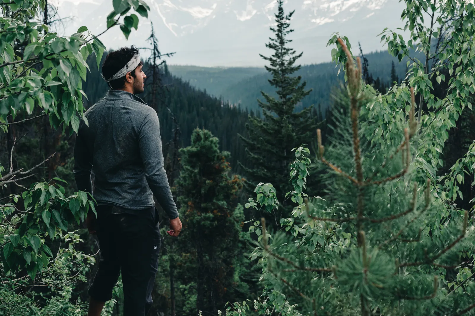 A hiker standing on a rocky outcrop looking toward distant mountains